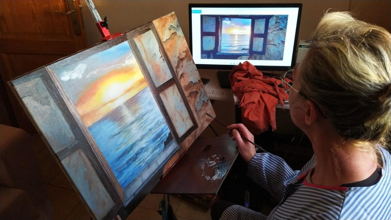 Eulari Alou pintando en su estudio frente a una obra en proceso.